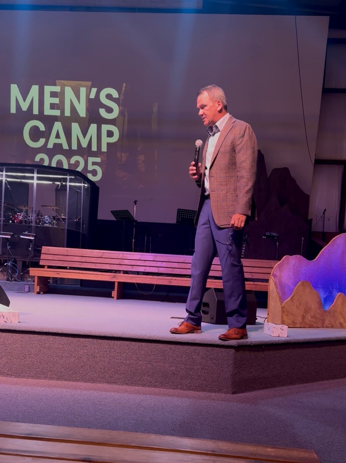 Speaker on stage with Men's Camp 2025 sign at Wisconsin men's conference