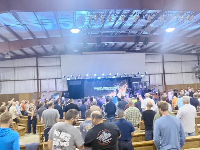 Wide auditorium view of men standing through the service.